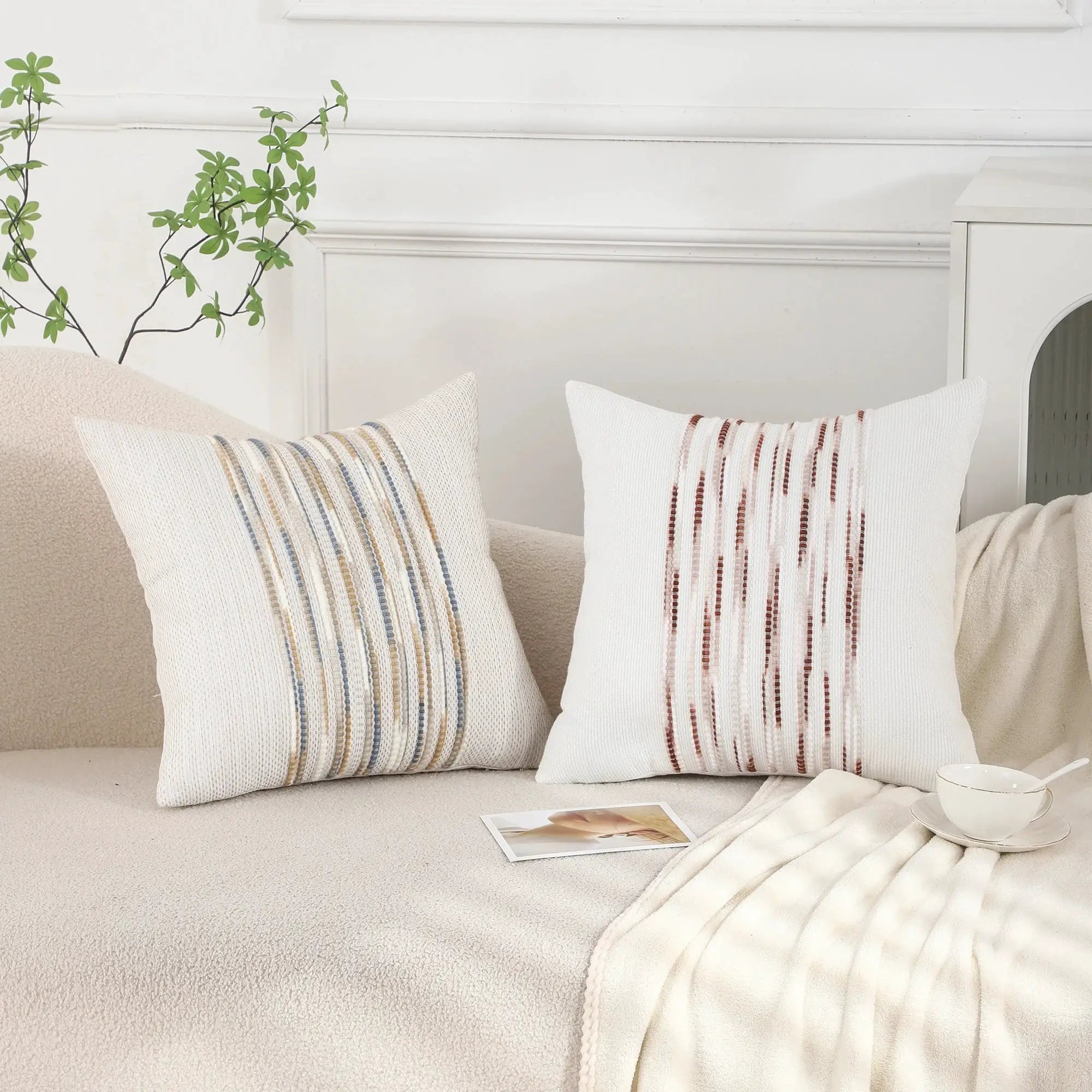 Three decorative boho striped chenille pillow covers, 18x18, white with blue and tan stripes, on sofa
