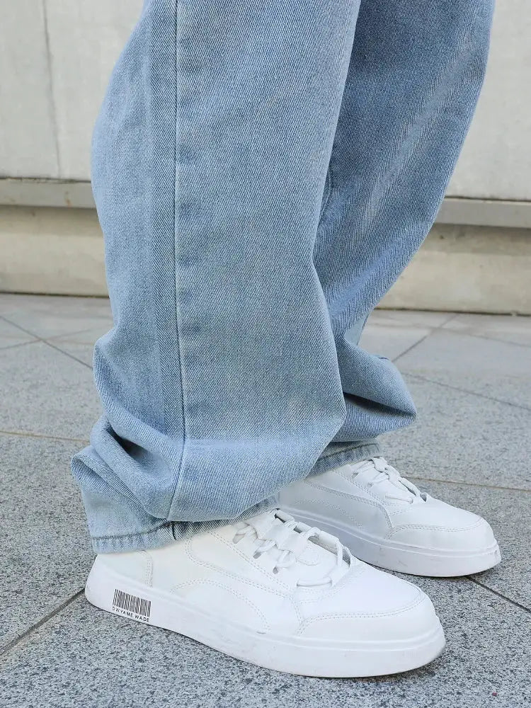 Men's baggy light-blue denim jeans with loose, wide straight legs and white sneakers.