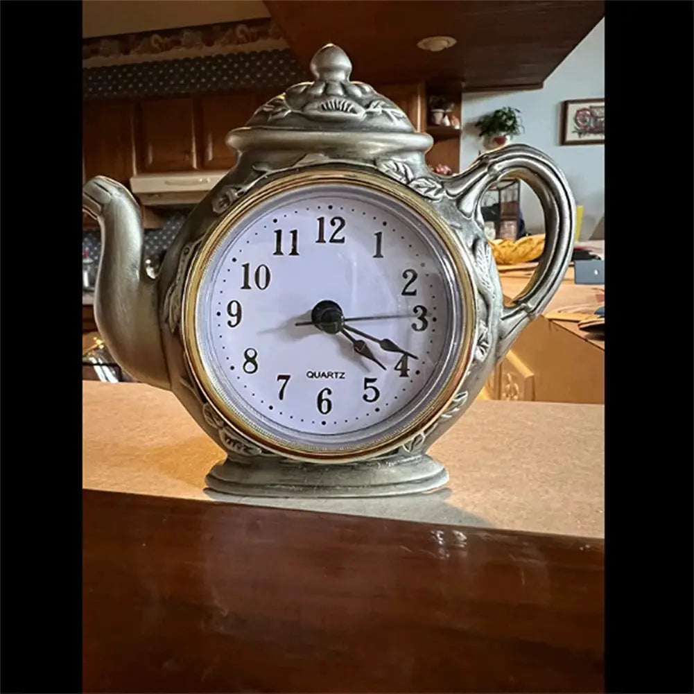 Teapot-shaped decorative clock with round white quartz face and antique silver finish