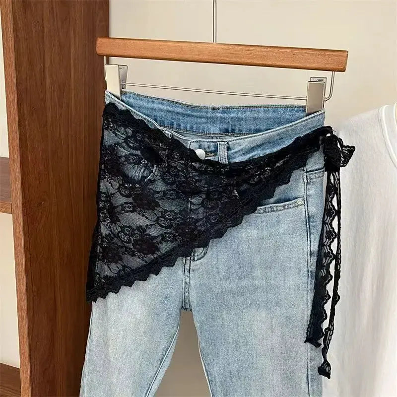 Denim jeans with black lace waist overlay and wrap-around lace belt, front view