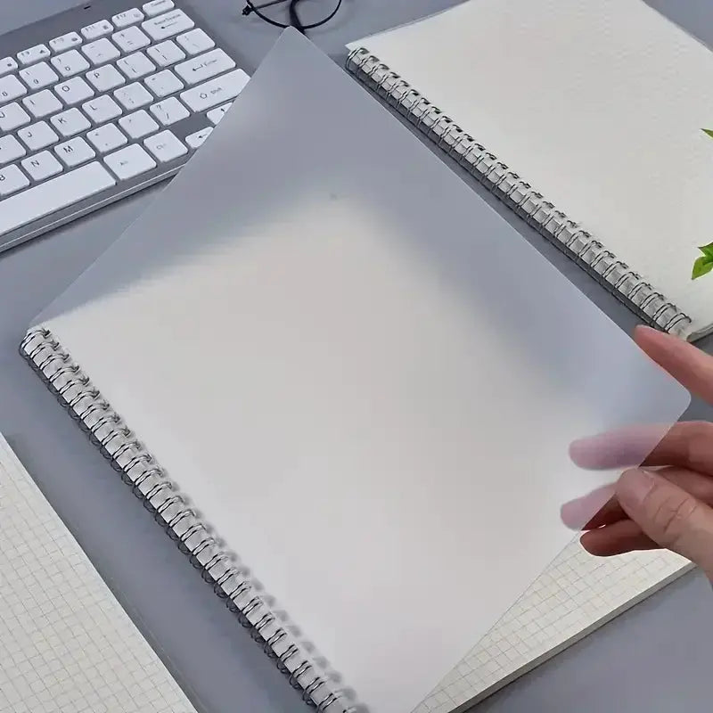 Simples Market Grid Notepads A5 spiral notebooks; two shown with a transparent sheet being peeled