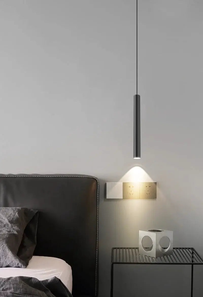 Minimalist bedside pendant lamp by Simples Market, cylindrical metal LED hanging light over the bed.
