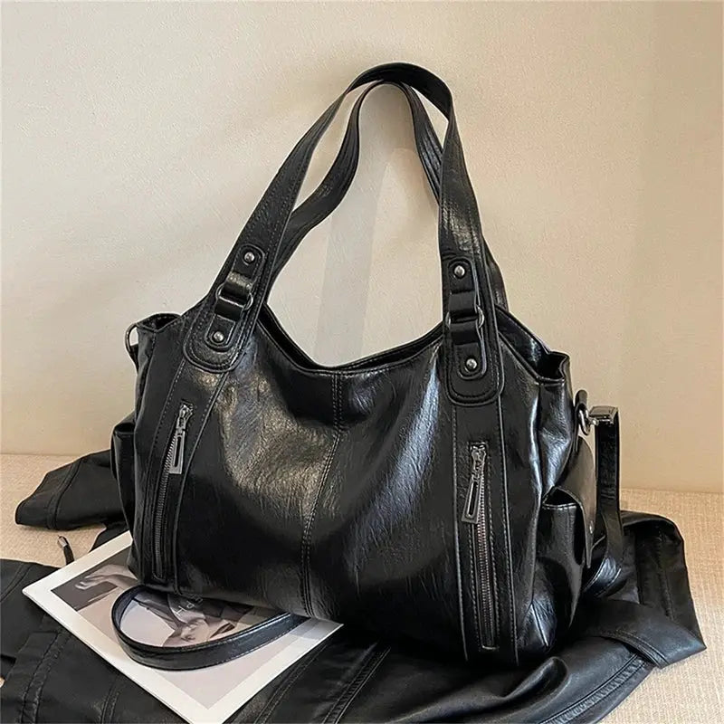 Black PU leather shoulder bag with soft interior compartments, dual top handles, and outer zipper pockets