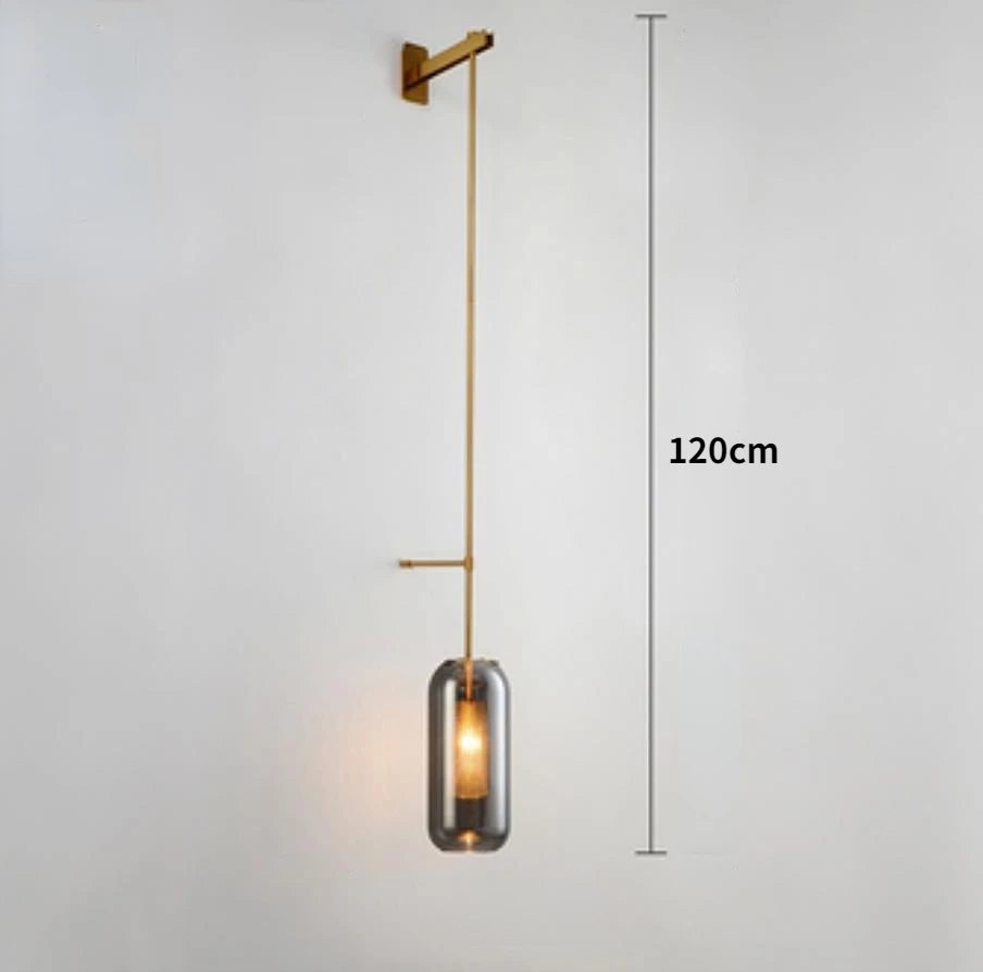 Modern glass wall light sconce, brass finish with cylindrical glass shade and LED bulb.