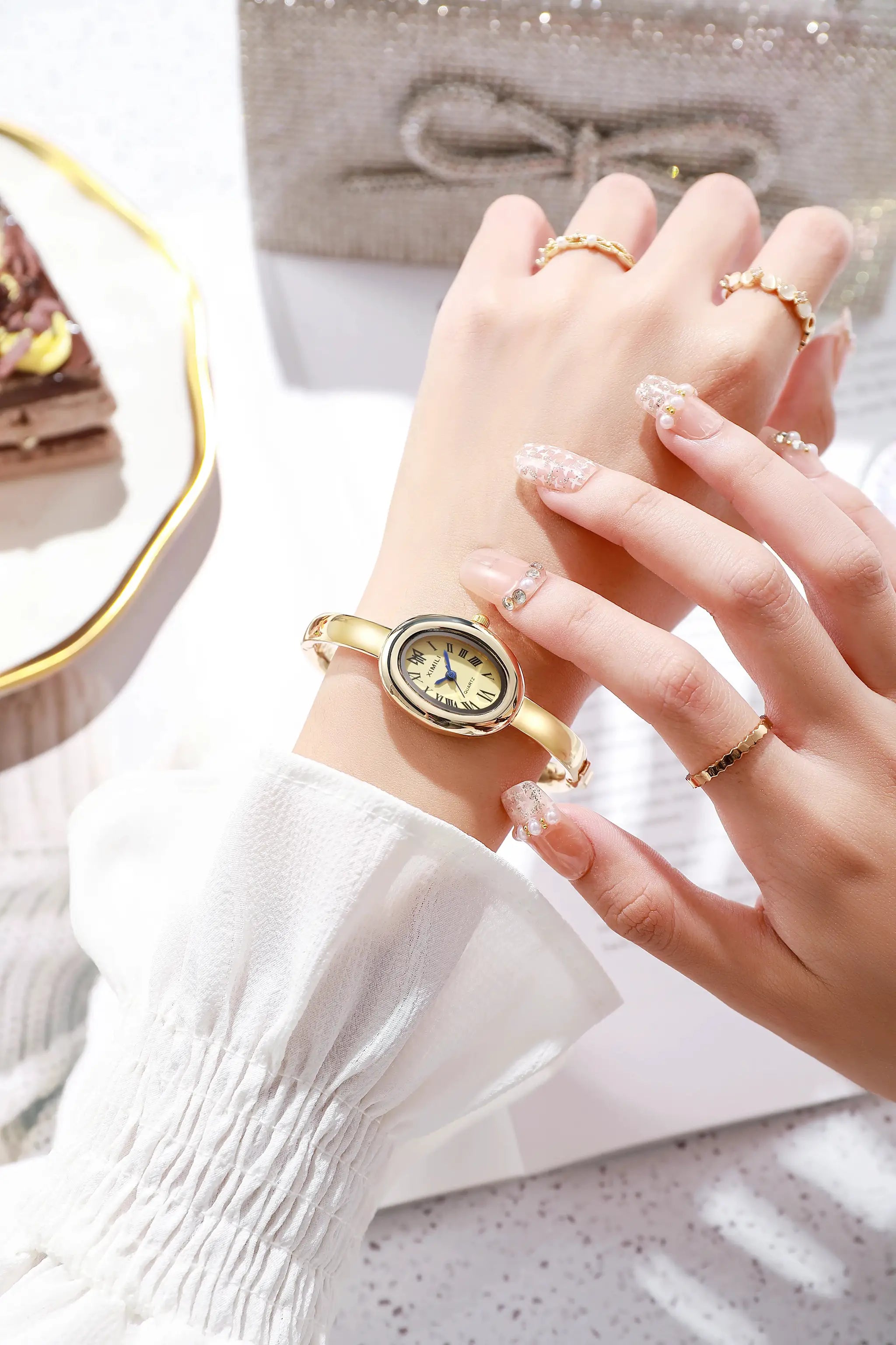 Simples Market women's gold-tone quartz dress watch with oval dial and metal band.