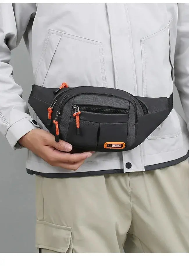 Oxford waterproof waist bag in black with orange zipper pulls worn around the waist.