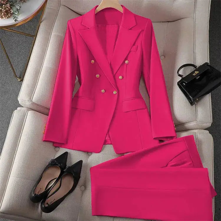Pink women's two-piece blazer and pants suit with gold buttons; black flats and a small black handbag.