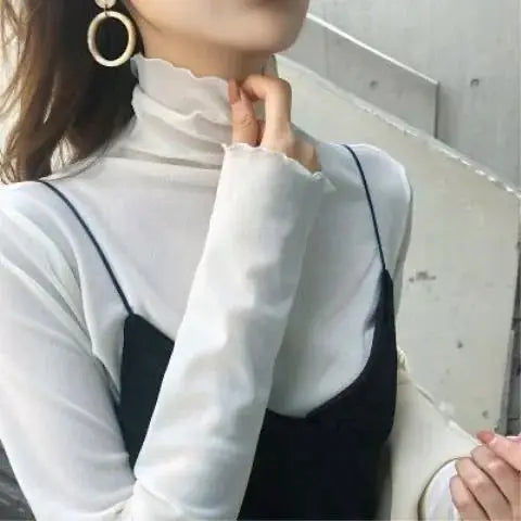 White sheer mesh blouse with long sleeves and high ruffle neck over a black camisole