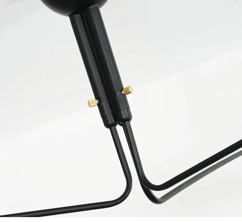 Pendant light by Simples Market in black metal with curved arms and gold knobs.