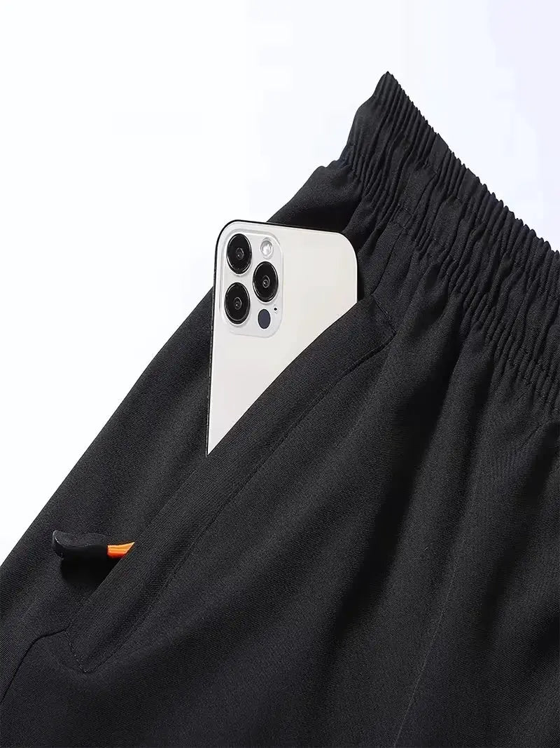Black men's sports shorts with elastic waistband and breathable fabric; phone peeking from pocket