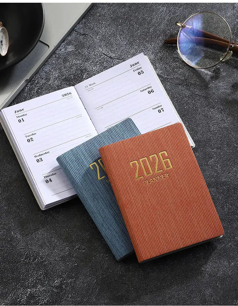 Simples Market A7 2026 pocket planners; two slim weekly calendars in orange and blue with open June pages