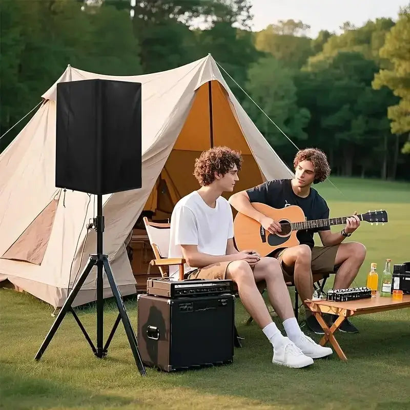 Durable black 210D Oxford cloth speaker cover on outdoor speaker setup beside a tent; two men play guitar.