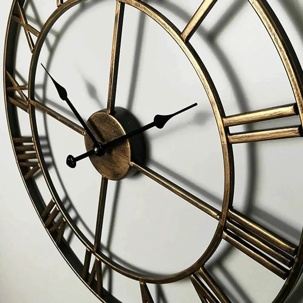 Large round metal wall clock with Roman numerals, brass finish, open skeleton frame and black hands