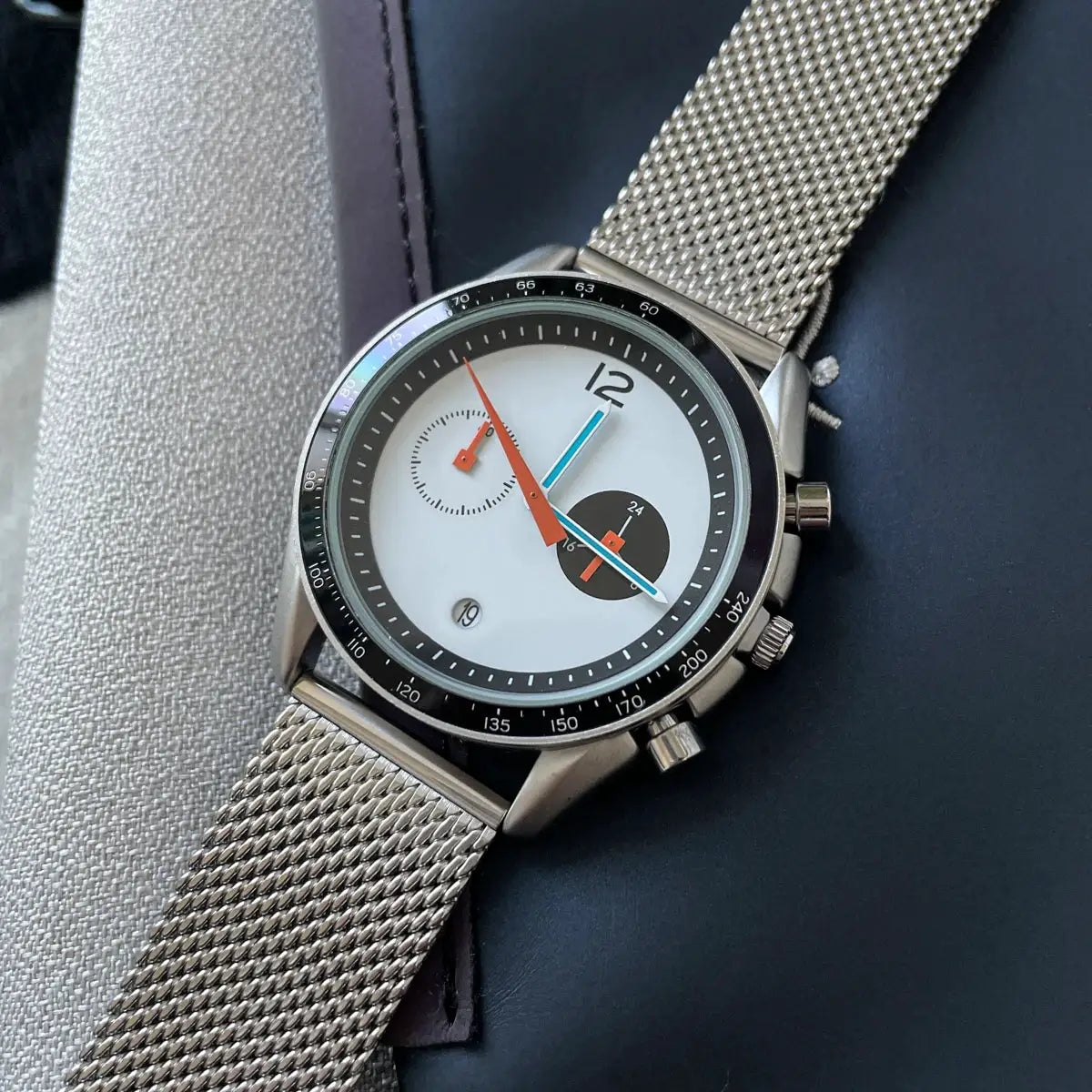 CILOA men's stainless steel mesh-band wristwatch with white dial and black tachymeter bezel.