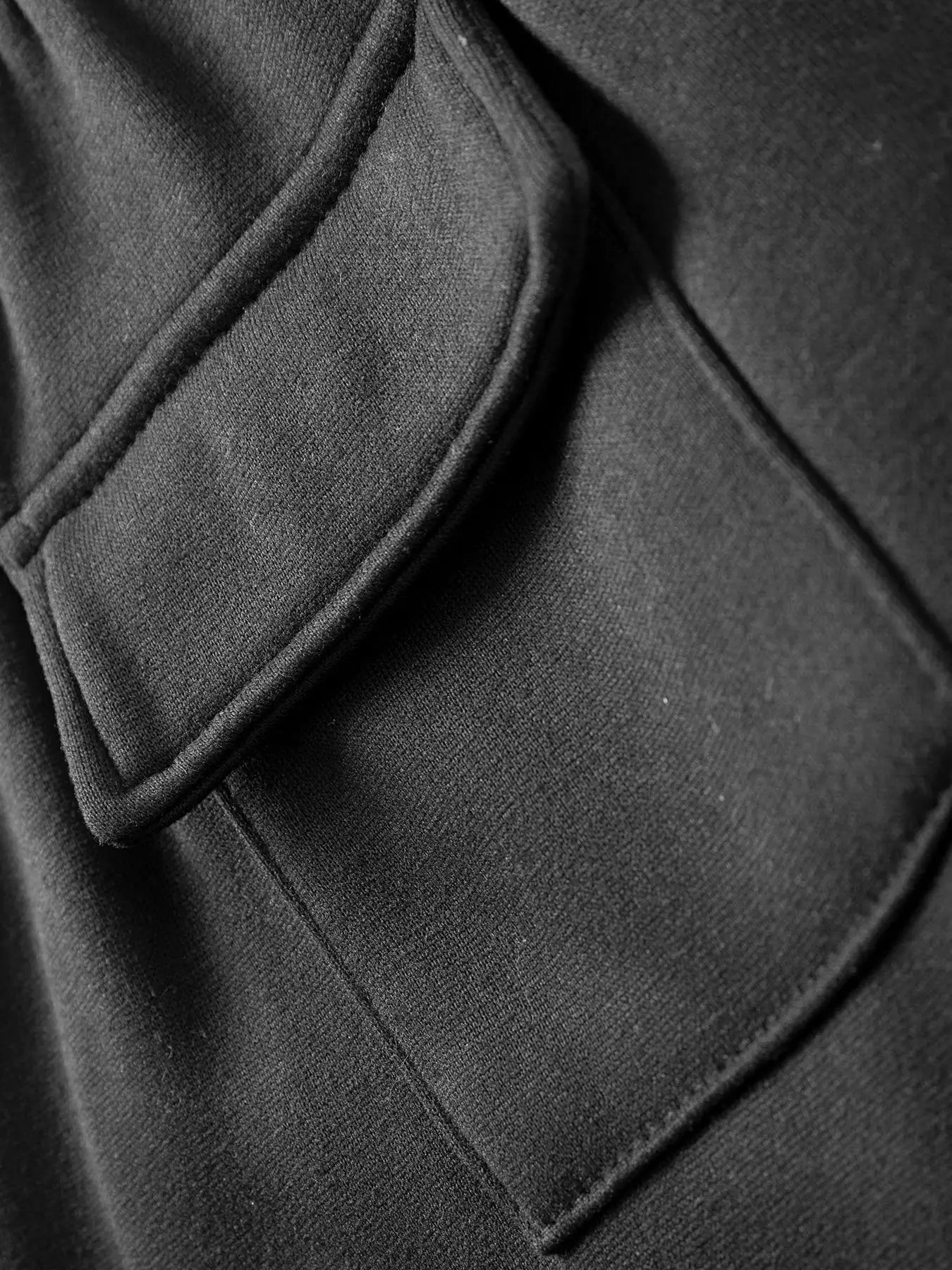 Men's black sweatpants by Simples Market; close-up of pocket seam and soft fabric.
