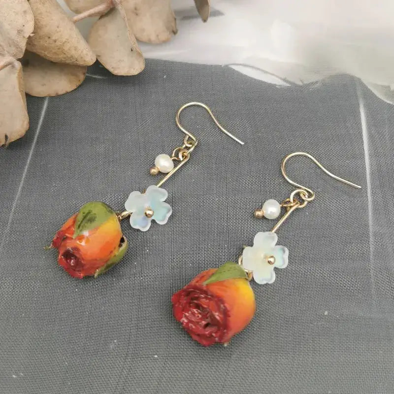 Unique red rose epoxy resin earrings with blue flower charms and pearl beads on gold-tone hooks (pair)