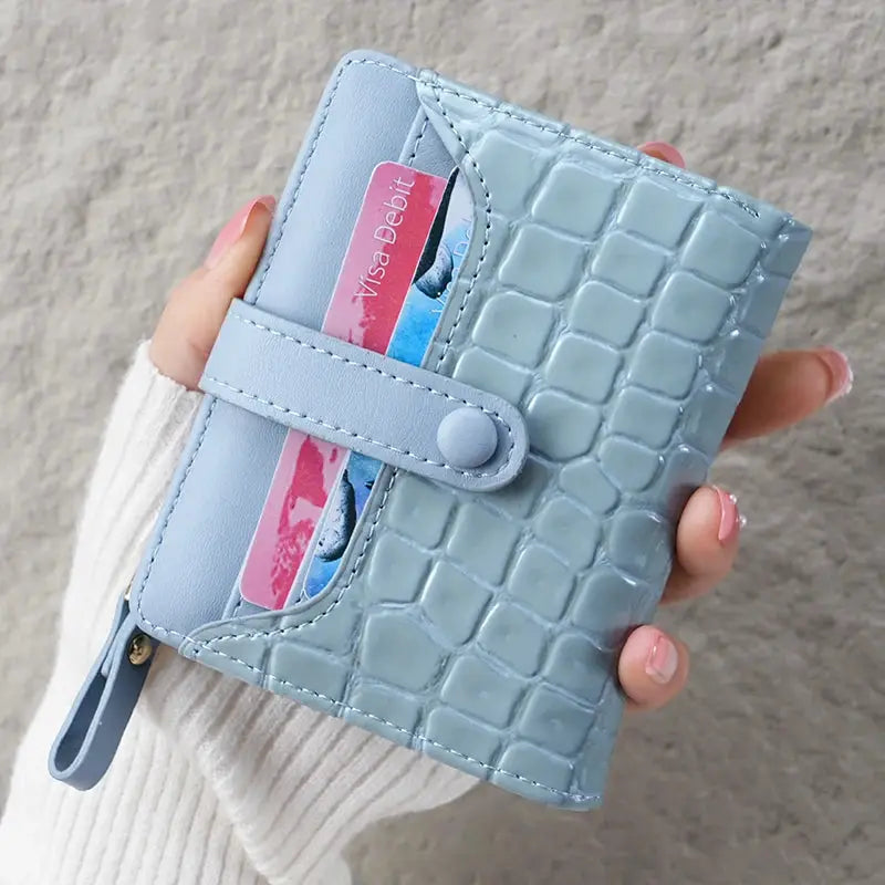 Mini crocodile-print clutch wallet in light blue with card slots and snap strap