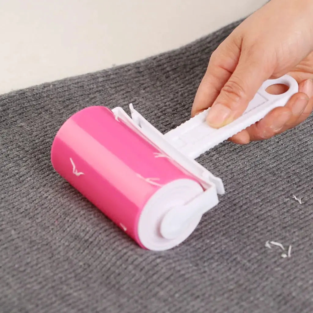 Pink handheld sticky lint roller for pet hair, reusable with peel-away adhesive sheet.
