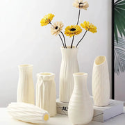Five white Nordic plastic vases with ribbed and geometric textures for flower display.