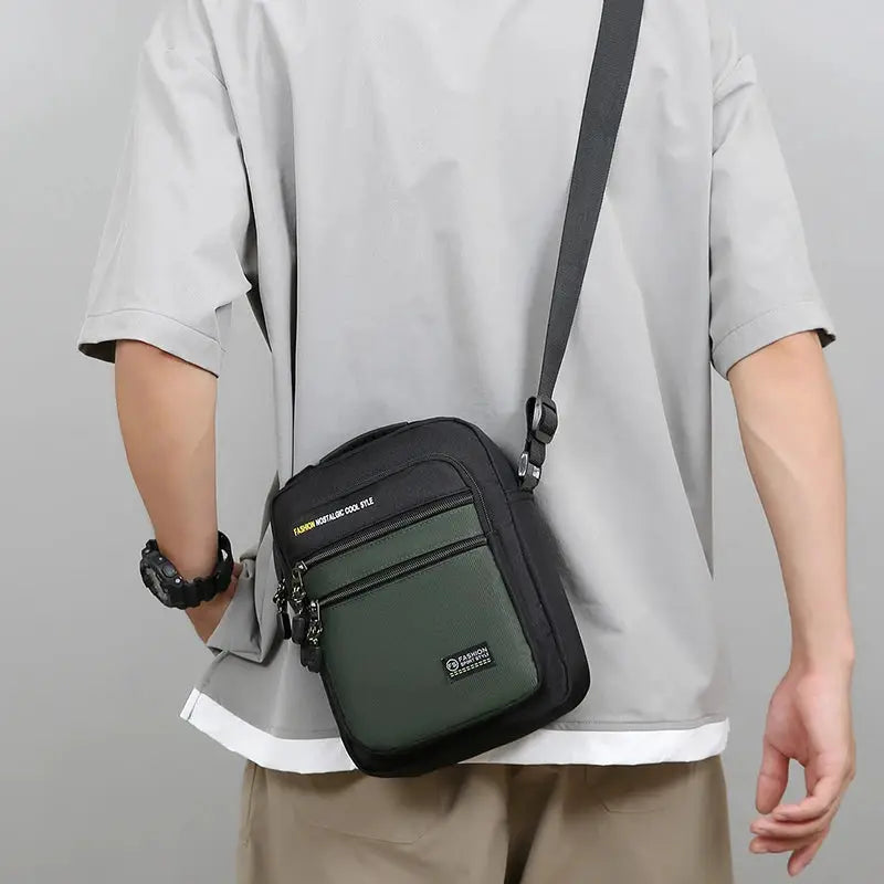 Men's Oxford crossbody bag with black body and green front pocket, multi-pocket storage