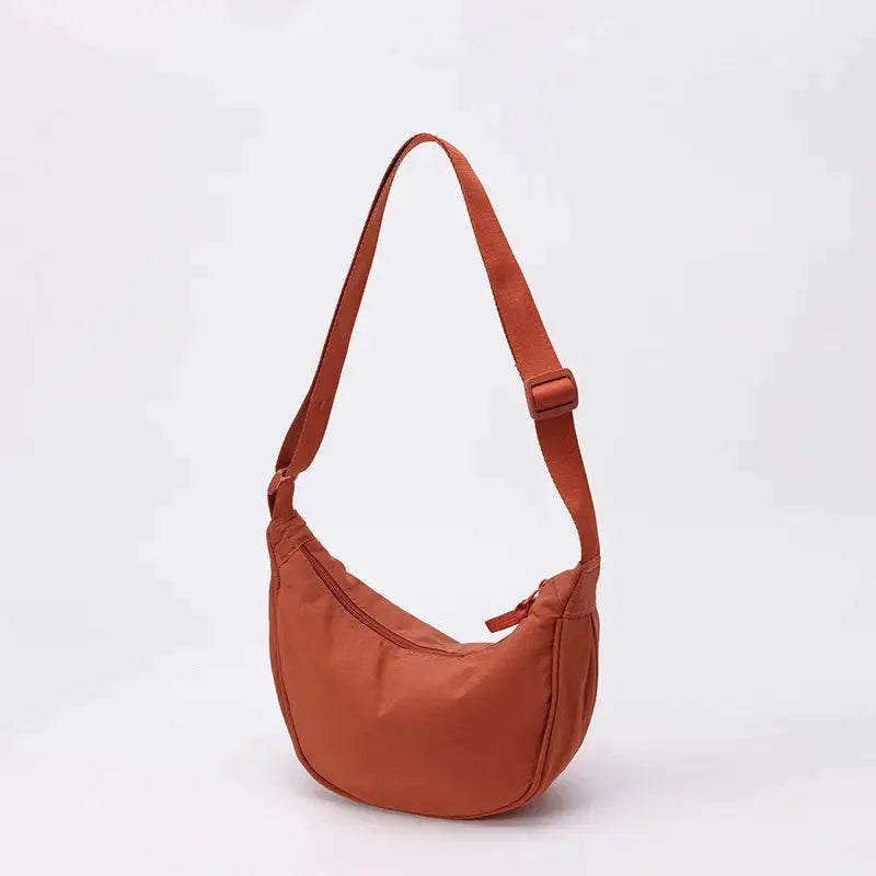 Nylon crescent-shaped crossbody dumpling bag in orange by Simples Market with adjustable strap, large capacity