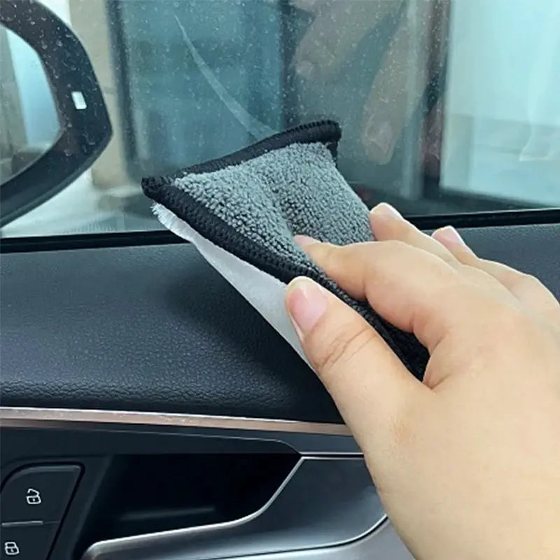 Microfiber scrubbing sponge for car detailing; soft double-sided gray/black sponge used on a car door panel