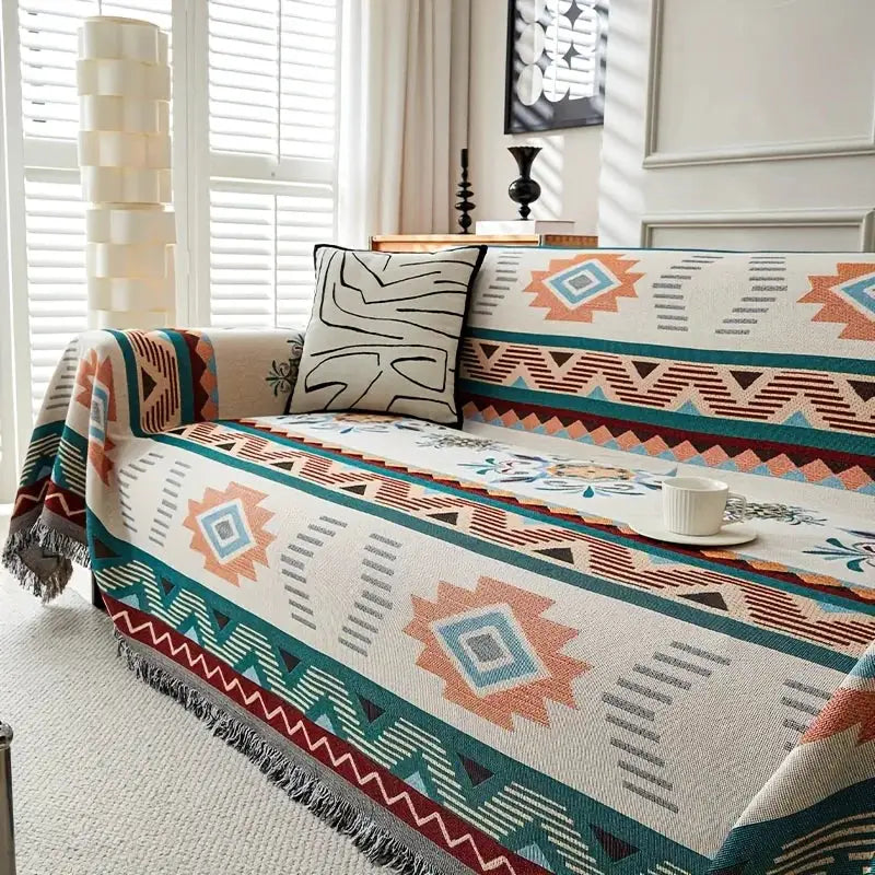 Ethnic sofa cover by Simples Market in turquoise and coral geometric pattern with fringed edges on a beige sofa.