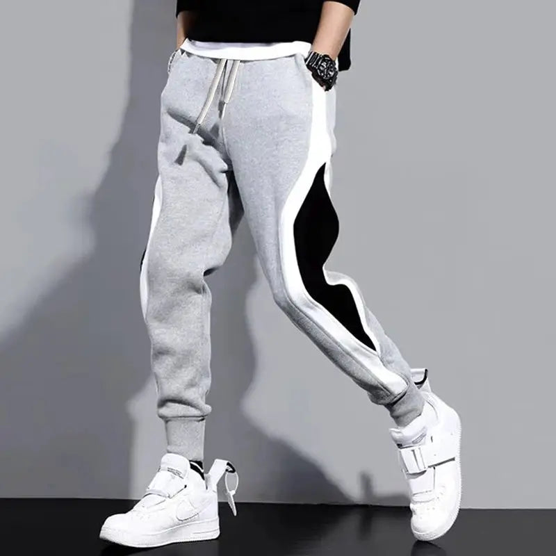 Men's patchwork jogger pants in gray with white side panels and black accents, drawstring waist, cuffed ankles