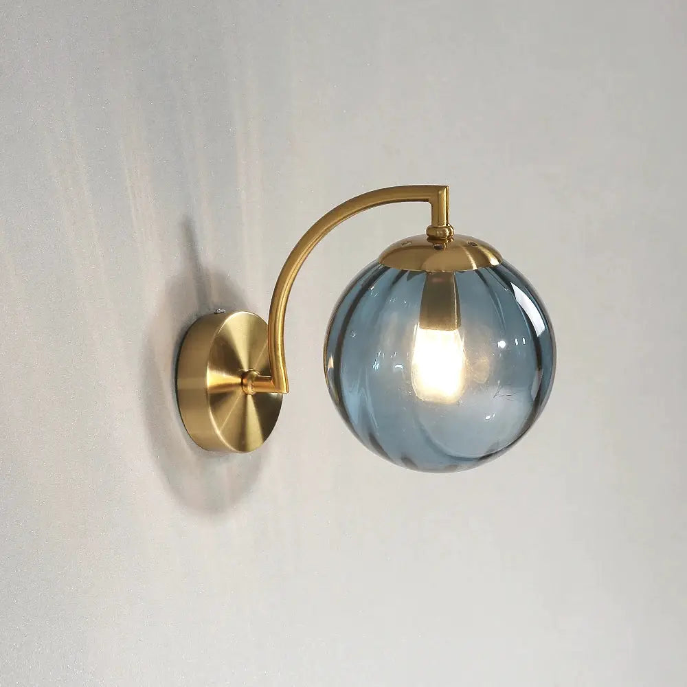 Modern LED wall lamp by Simples Market with brass curved arm and blue glass globe sconce, ideal for living rooms.