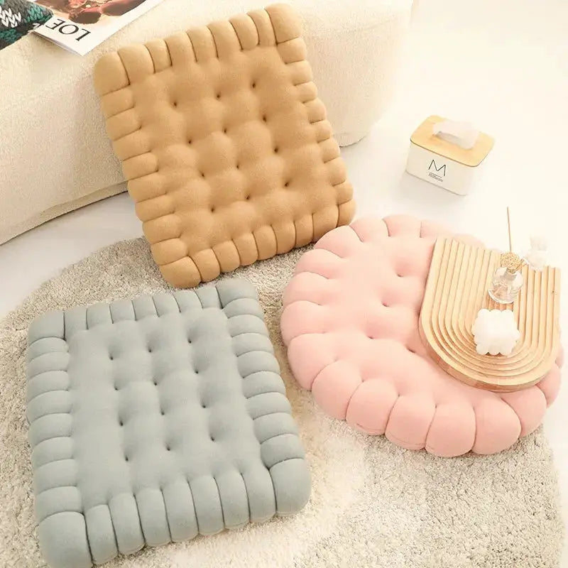 Large biscuit-shaped plush cushions, Simples Market set of three in tan, gray, and pink with tufted texture.