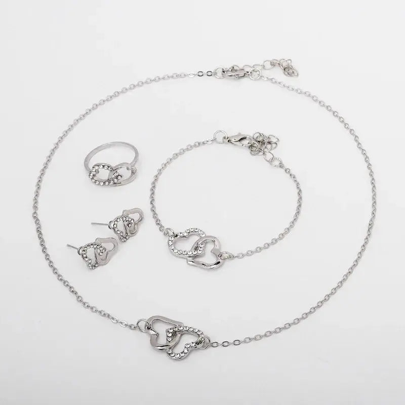 Five-piece silver-tone heart jewelry set with rhinestones, including necklace, bracelet, ring, and earrings