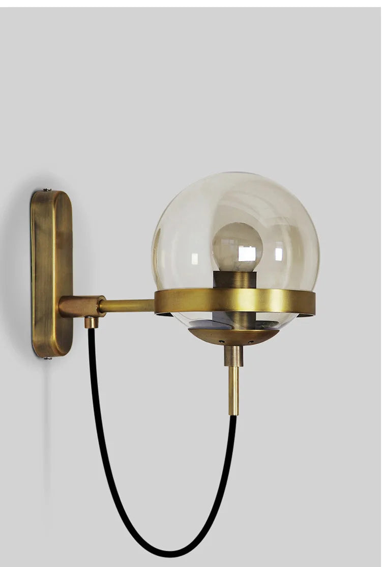 Simples Market modern glass ball wall lamp, brass finish with a clear globe and black cord