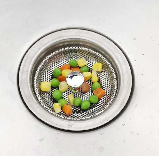 Stainless steel sink drain strainer with perforated mesh; multicolored chunks visible inside