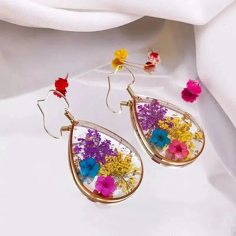 Colorful pressed-flower teardrop earrings in clear epoxy resin with gold-tone frames
