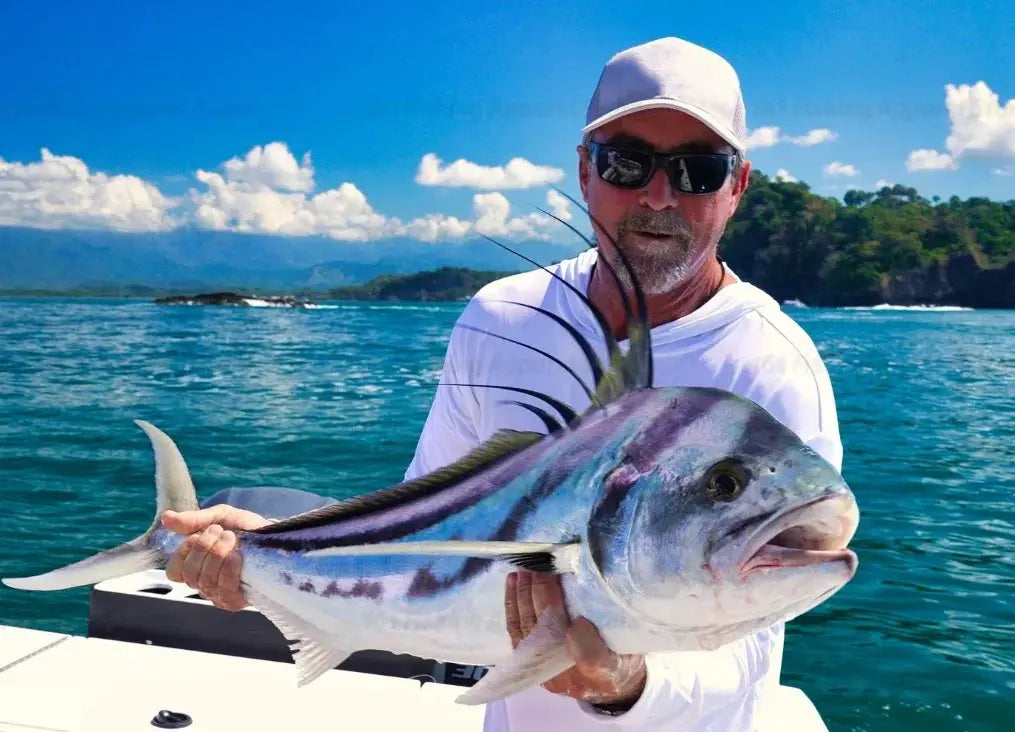 Men's white fishing shirt with long sleeves and UV protection, shown on a man holding a large striped fish.