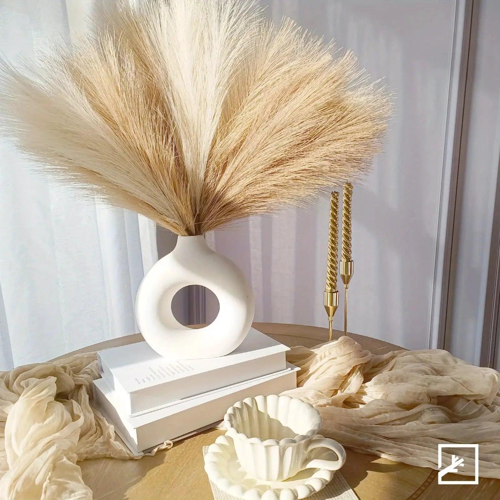 Pampas grass decor stems, 6pc, beige in a white ceramic vase with circular cutout on a stack of books