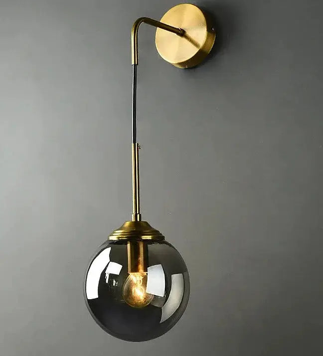 Modern glass wall lamp by Simples Market, gold sconce with smoky round glass globe.