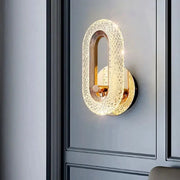 Wall lamp by Simples Market; oval crystal acrylic shade on a gold-finish iron base, LED bedroom sconce.