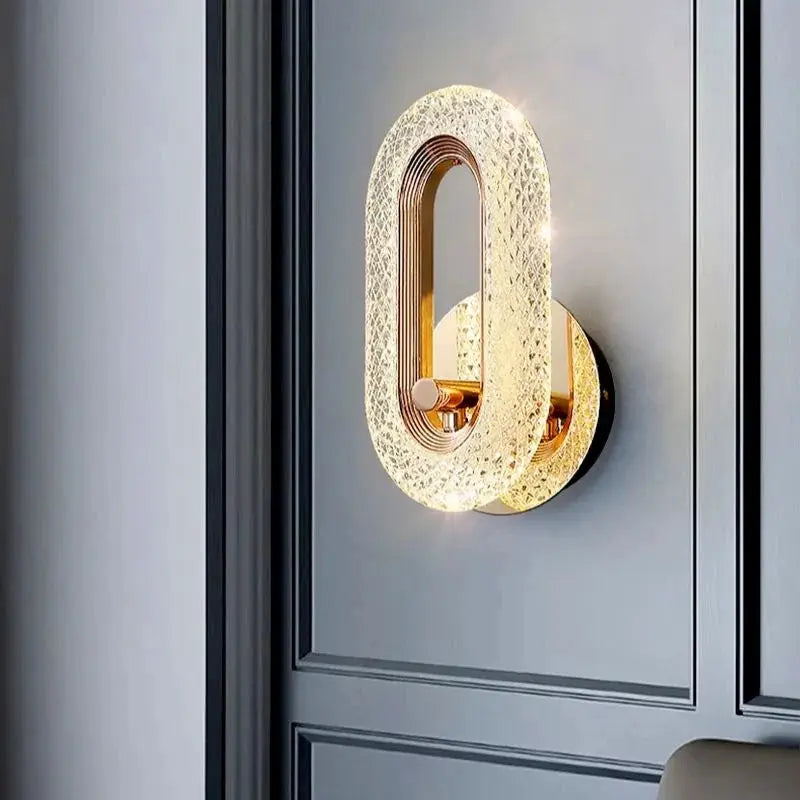 Wall lamp by Simples Market; oval crystal acrylic shade on a gold-finish iron base, LED bedroom sconce.
