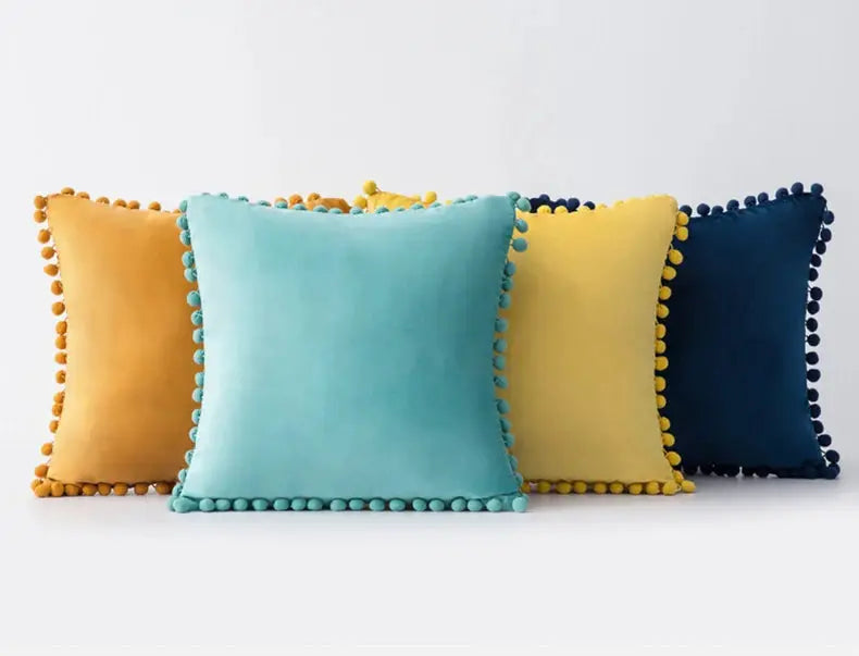 Velvet cushion covers set of four with pom-pom fringe in orange, turquoise, yellow, and navy.
