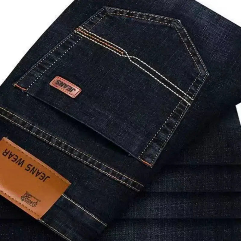 Men's straight denim jeans in dark blue stretch fabric with back pocket patch and orange stitching.