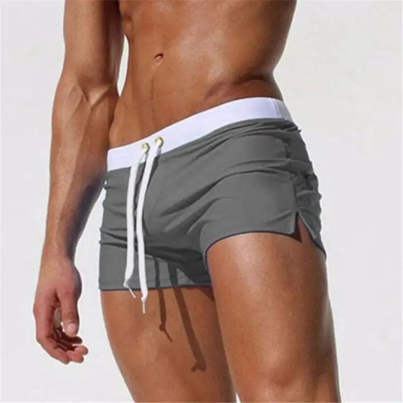 Men's grey-green quick-drying swim trunks with white waistband and drawstring.