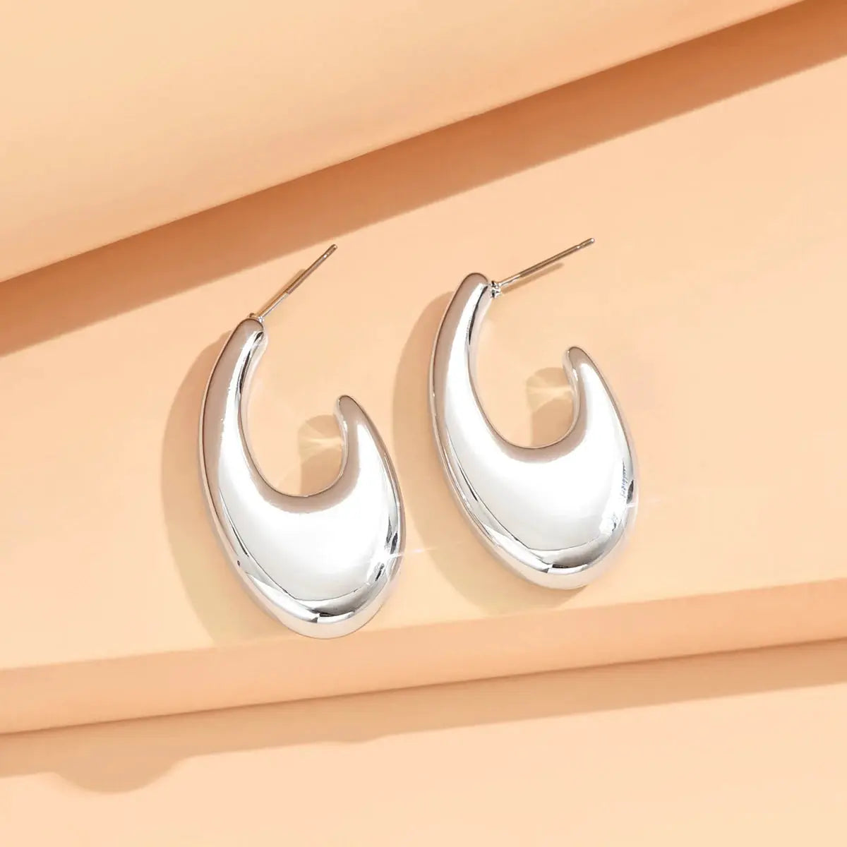 Pair of silver crescent-shaped hoop earrings with a polished metal finish for women.