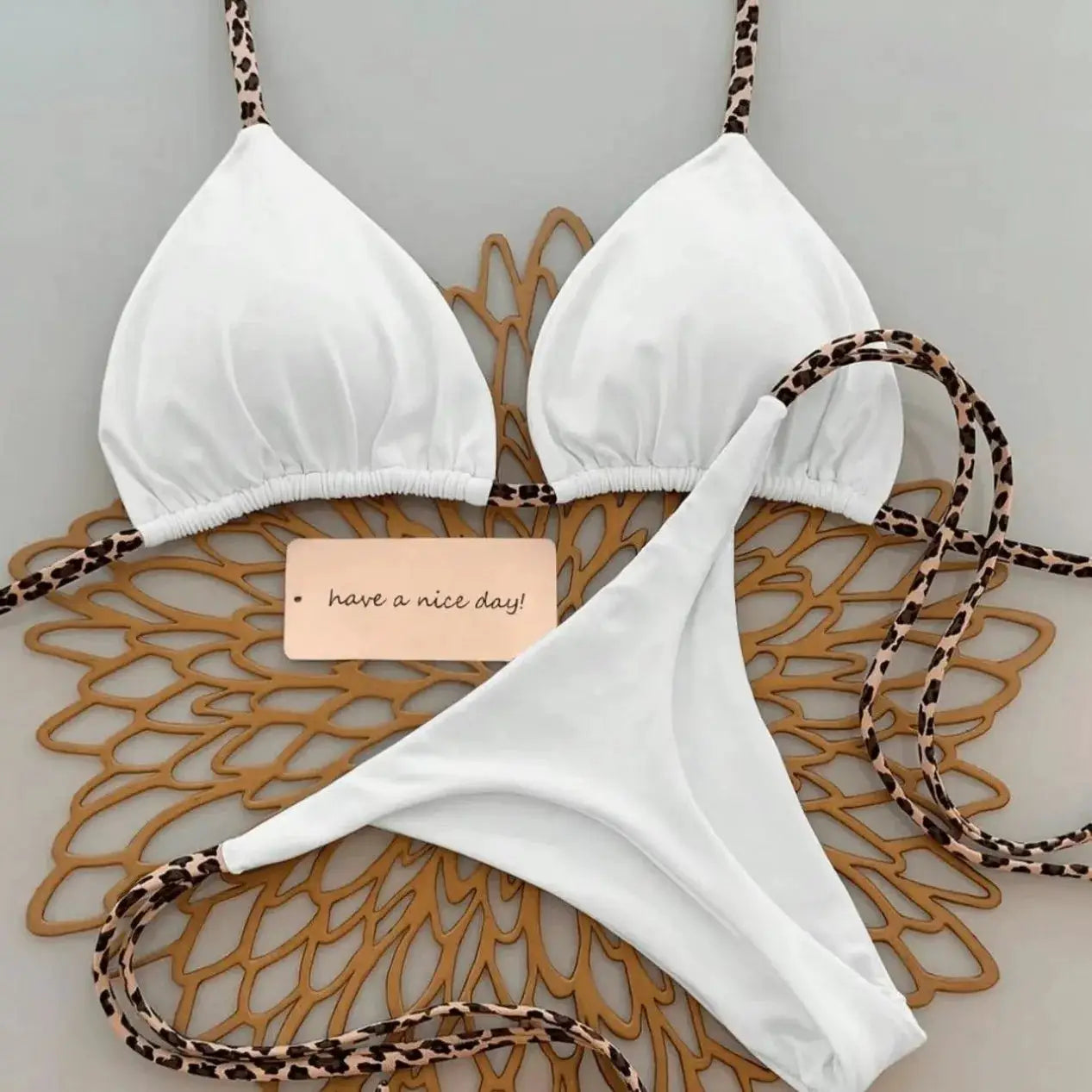 Bikini set by Simples Market: white with leopard-print straps, triangle top and thong bottom.