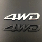 Two 3D metal 4WD car emblems in chrome and black finishes.