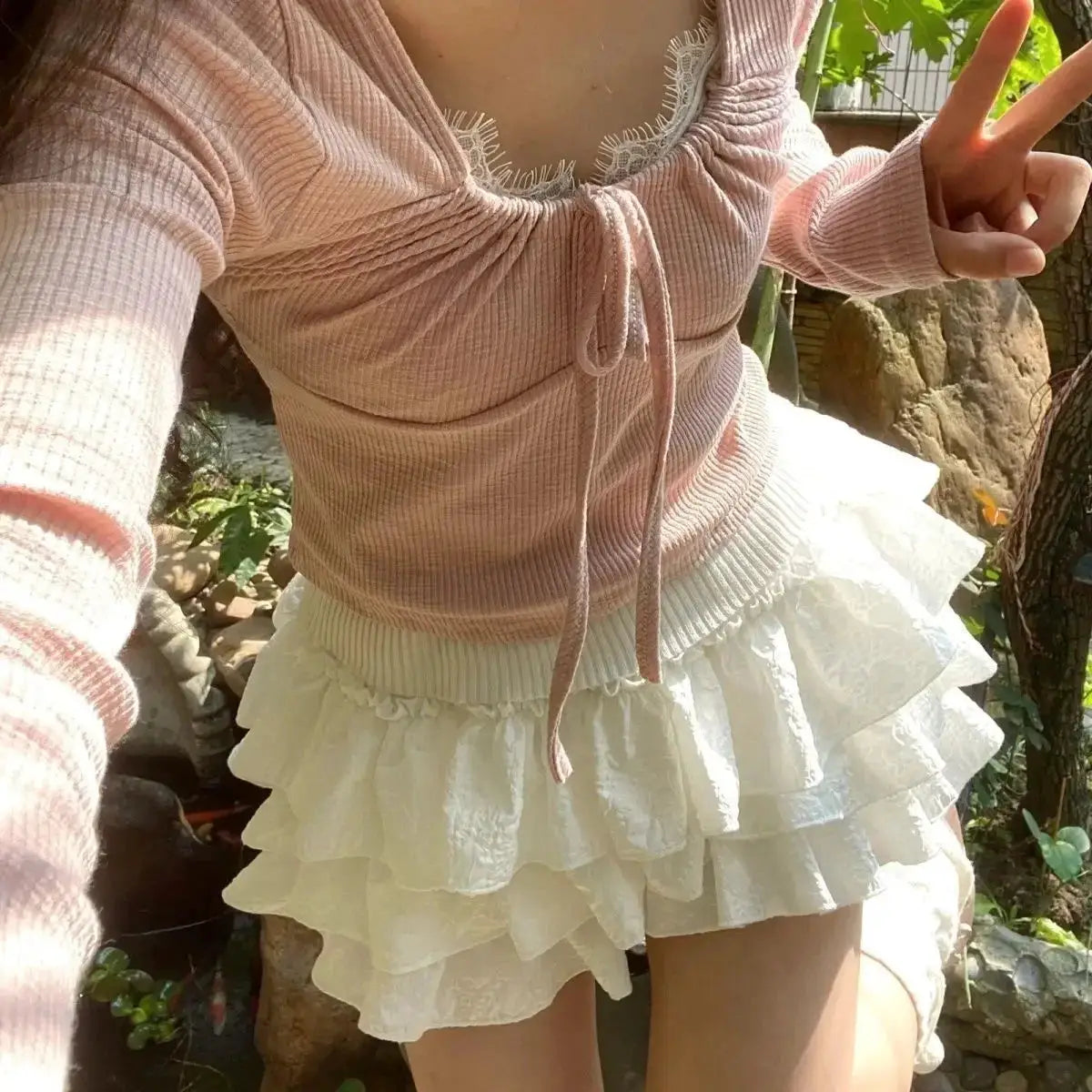 Kawaii layered white ruffle mini skirt with elastic waist, paired with pink knit top.