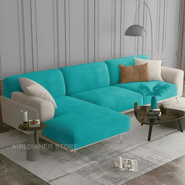 Teal velvet sectional sofa with cream armrests and cushions on a light rug in a modern living room scene.