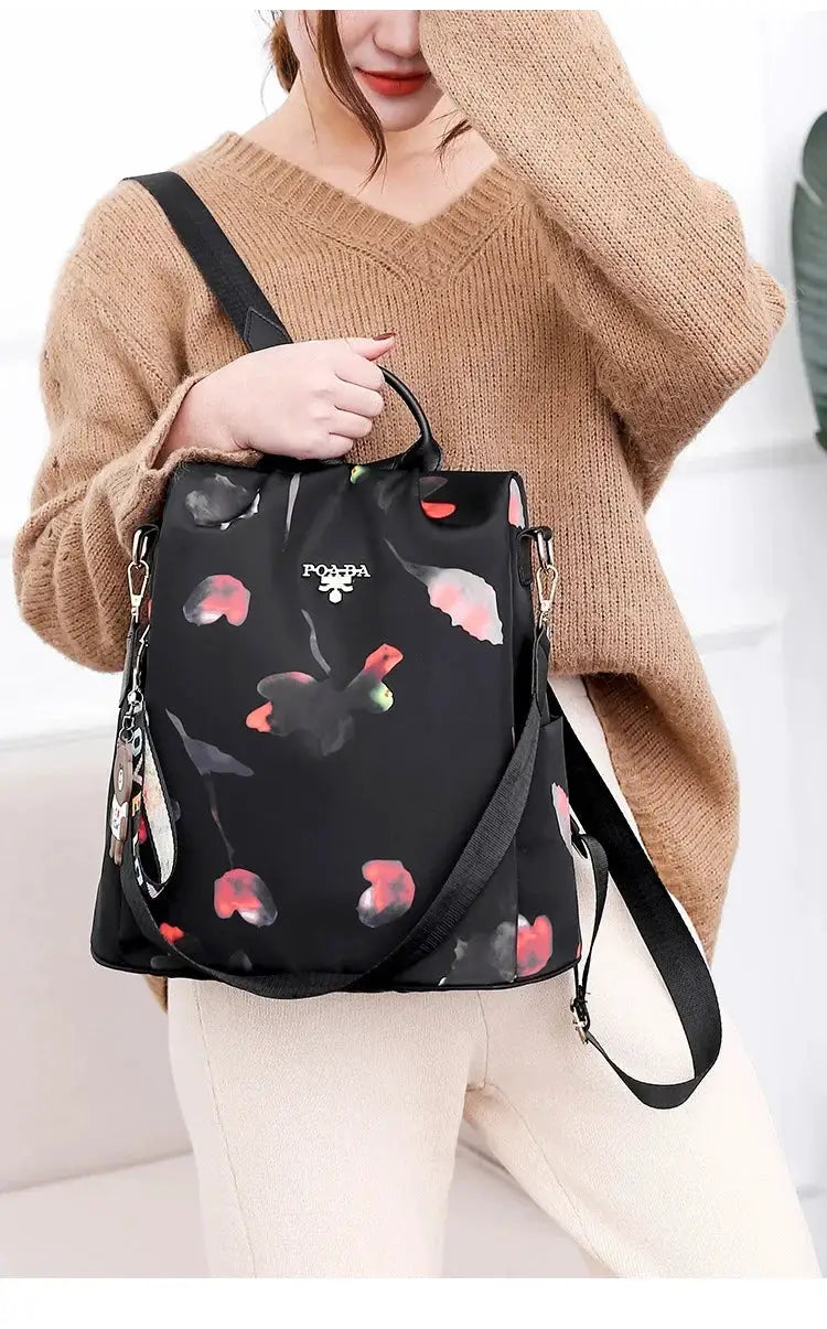Simples Market women's backpack with floral print on black Oxford cloth; top handle and adjustable shoulder strap