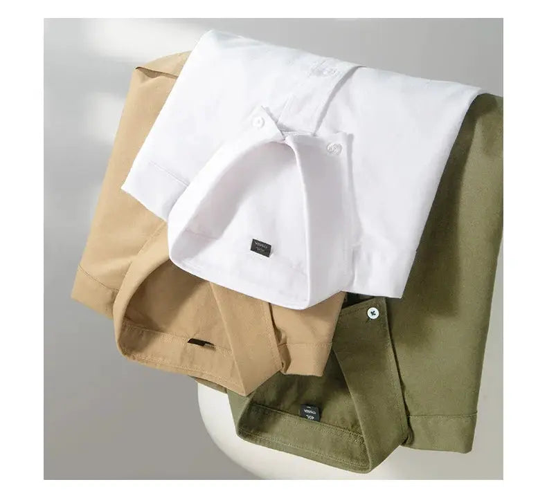 Three men's long-sleeve cotton oxford shirts in white, beige, and olive green, each with a single pocket.