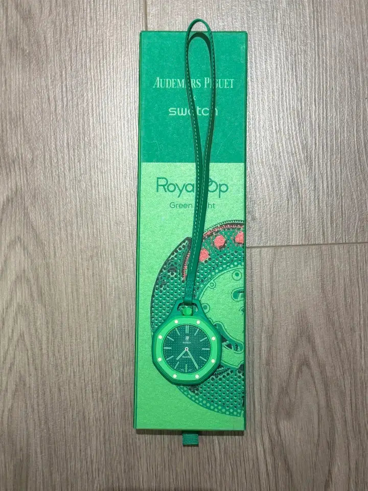 Watch green quartz wristwatch with matching green strap on a green Swatch box packaging